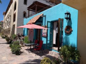 a blue building with a table and a pink umbrella at Casa Patricia in Loreto