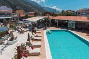 a resort with a swimming pool and chairs and a building at Bronze Hotel in Oludeniz