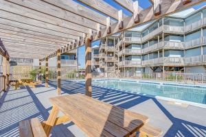 a patio with a wooden table and a swimming pool at Daly Vibes in Rodanthe