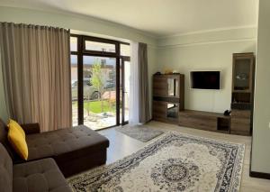 ein Wohnzimmer mit einem Sofa und einem TV in der Unterkunft Таунхаус на Иссык Куле Baytur Resort in Bosteri