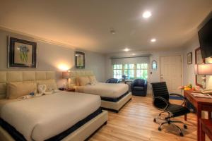 a hotel room with two beds and a desk at Pleasant Bay Village Resort in Chatham