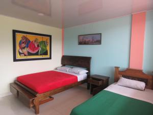 a bedroom with two beds and a painting on the wall at Finca Hotel Guayacundo in Vergara