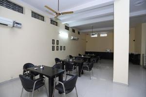 a dining room with tables and chairs and a ceiling at Capital O 7302 The Huespedes in Gurgaon