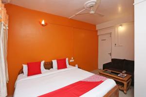 a bedroom with orange walls and a bed with red pillows at New Mega Palace in Bankipur