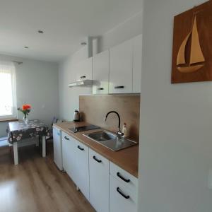 eine Küche mit weißen Schränken und einem Waschbecken in der Unterkunft Kurka Wodna - Apartamenty na Mazurach in Dłużek