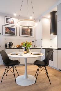 uma cozinha branca com uma mesa e 2 cadeiras em Manufaktura Modern Industrial Apartment em Lódź
