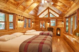 Big Sur Campground and Cabins في بيج سور: سريرين في غرفة بجدران خشبية ونوافذ