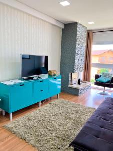 a living room with a blue cabinet with a flat screen tv at apartamento em gramado in Gramado