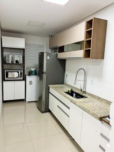 a kitchen with white cabinets and a stainless steel refrigerator at apartamento em gramado in Gramado