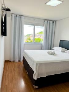 a bedroom with a large bed and a window at apartamento em gramado in Gramado