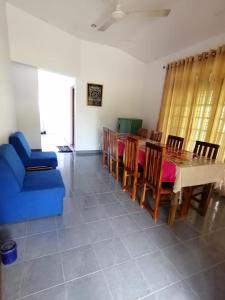 un soggiorno con divano blu, tavolo e sedie di Night Jusmine Holiday Home a Anuradhapura