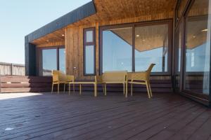 eine Terrasse mit Stühlen, einem Tisch und Fenstern in der Unterkunft Casas Punta Costanera in Pichilemu
