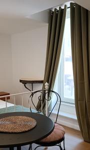 a table and chairs next to a window with curtains at M&R Apartments I in Koper