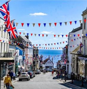 a street with british flags and people walking down the street at Quirky Lyme Regis Apartment Near Beach in Lyme Regis