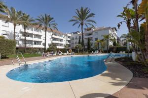 una gran piscina con palmeras y edificios en Stunning Duplex 5 minutes from Puerto Banús, en Marbella