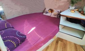 a small bed in a room with purple sheets and pillows at 1 ou 2 chambres cosy sur une charmante pénichette de 11 m - Pour plus de détails, veuillez consulter notre profil in Marseillan