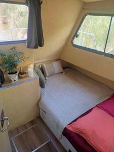 a small bed in the corner of a tiny house at 1 ou 2 chambres cosy sur une charmante pénichette de 11 m - Pour plus de détails, veuillez consulter notre profil in Marseillan