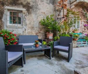 a patio with three chairs and a table and a building at Room Kaštelan in Cres