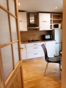 a kitchen with white cabinets and a black chair at Elegant Old Town Toffee Bliss Apartment, SELF Check-In, Steps from Bus Station in Riga