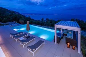 una piscina con sillas y un cenador por la noche en Villa Aura Caesar - 5 Bedroom villa - Ultra modern and luxurious - Stunning sea and town views, en Medveja