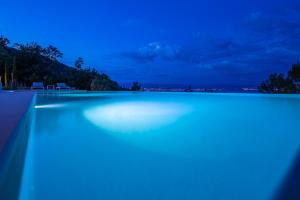 una piscina iluminada por la noche con luces azules en Villa Aura Caesar - 5 Bedroom villa - Ultra modern and luxurious - Stunning sea and town views, en Medveja