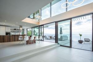 an open kitchen and dining room with glass walls and floor to ceiling windows at Stunning Kvarner Villa 5 Bedrooms Villa Aura Caesar Stunning Sea Views & Private Pool Opatija in Medveja