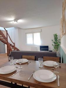 a wooden table with plates and wine glasses on it at ° Appart' Audincourt 2 centre ° in Audincourt