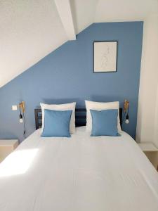 a large bed with blue walls and two blue pillows at ° Appart' Audincourt 2 centre ° in Audincourt