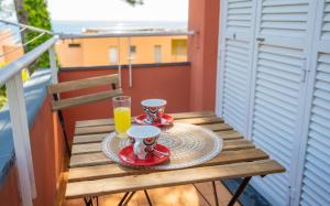 een houten tafel met twee kopjes en een glas sinaasappelsap bij [Suite con Piscina] WiFi - Netflix - Mare a 7 Min in Varazze