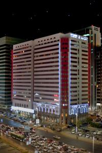 um grande edifício branco com janelas vermelhas numa cidade em City Seasons Al Hamra Hotel em Abu Dhabi