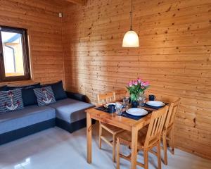 a dining room with a table and a couch at Domki Letniskowe Na Slonecznym Wzgorzu in Władysławowo