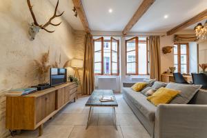 ein Wohnzimmer mit einem Sofa und einem TV in der Unterkunft L'élégance de la pierre au pied de la Maison Carrée - Une Nuit à Nîmes in Nîmes