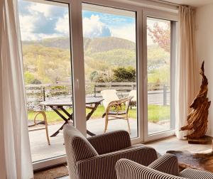 een woonkamer met een balkon met een tafel en stoelen bij Natur Panorama Suiten am Rursee in Heimbach