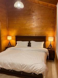 una camera da letto con un grande letto bianco con due lampade di أكواخ وشاليهات باشن الريفية a Khalij Salman