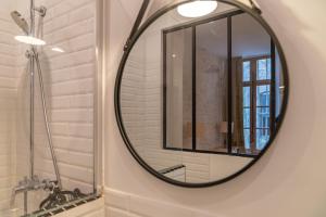 La salle de bains est pourvue d'un grand miroir rond sur le mur. dans l'établissement L'élégance de la pierre au pied de la Maison Carrée - Une Nuit à Nîmes, à Nîmes 22 autres photos