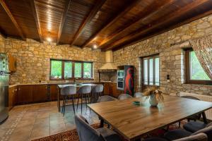 een keuken met een houten tafel en een stenen muur bij Πέτρινη εξοχική κατοικία, Λάρισα 
