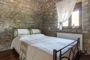 een slaapkamer met een bed in een stenen muur bij Πέτρινη εξοχική κατοικία, Λάρισα 