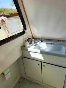 a bathroom with a sink and a window at 1 ou 2 chambres cosy sur une charmante pénichette de 11 m - Pour plus de détails, veuillez consulter notre profil in Marseillan