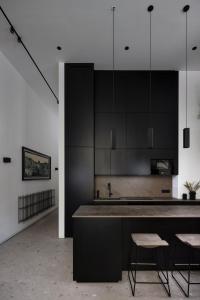 eine Küche mit schwarzen Schränken, einer Spüle und Stühlen in der Unterkunft City Center Apartment Telegraph in Wien
