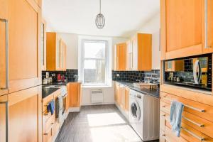 a kitchen with wooden cabinets and a washer and dryer at Tiny home at Dundee in Dundee