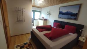 Habitación con cama con almohadas rojas. en Appartements Gerhard, en Telfes im Stubai