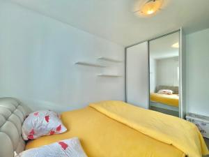 a bedroom with a yellow bed and a mirror at Family One bedroom apartment with Garden view in Budva