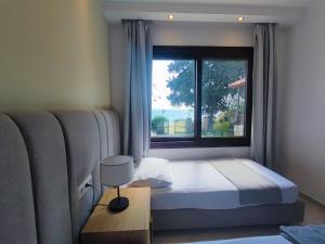 a bedroom with a bed and a large window at Mina's House Beachfront Apartments in Nikiti