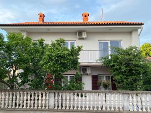 a white house with a white fence and trees at Apartment Bencic in Fažana