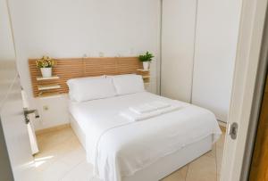 uma cama branca num pequeno quarto com plantas em Espectacular apartamento. em Benalmádena