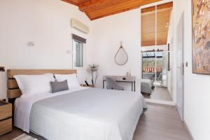 a white bedroom with a large bed and a balcony at MM luxury studios&villas in Kompítsion