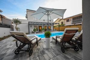 Un patio con dos sillas y una sombrilla junto a una piscina. en Villa Adria, en Privlaka