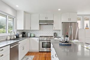 a kitchen with white cabinets and stainless steel appliances at Marbella Lane - Charming & Serene home in Pacifica in Pacifica