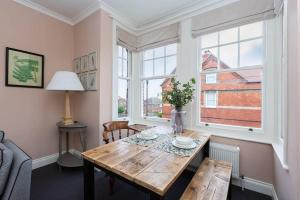 uma sala de jantar com uma mesa de madeira e 2 janelas em Harriet - Quaint one bedroom apartment with easy parking em Kent