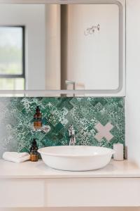 a white sink in a bathroom with a green tiled wall at Ludus Magnus Boutique Hotel in Franschhoek